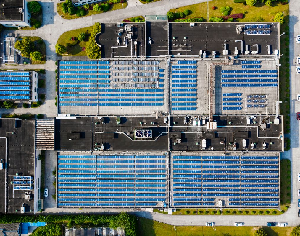 An aerial photo of solar panels on top of a large building.