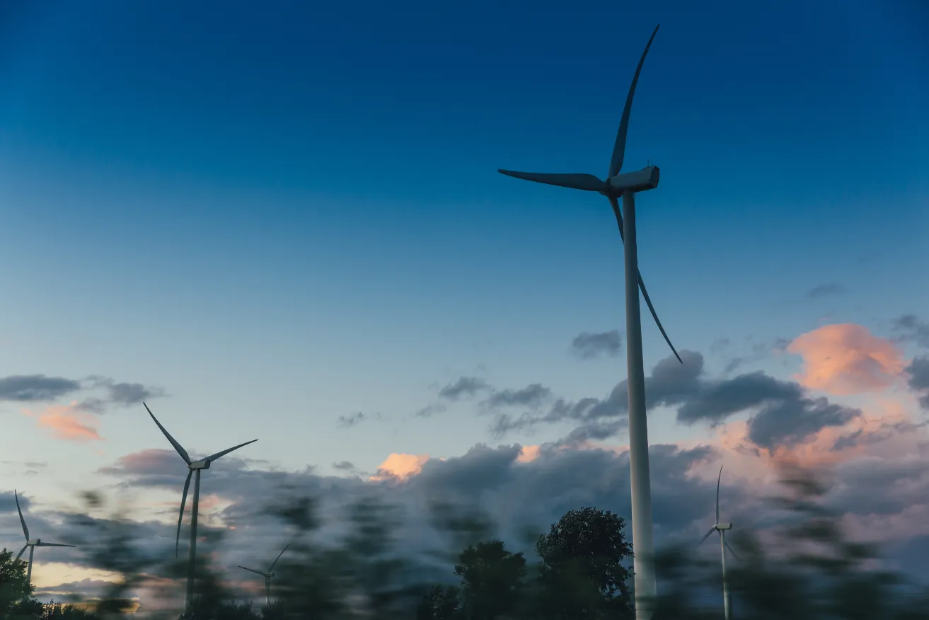 Photo of wind turbines in front of a dusk sky.